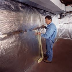 Installation of a radiant heat and vapor barrier on a basement wall in Knox