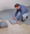 Contractors installing basement subfloor tiles and matting on a concrete basement floor in Franklin, Pennsylvania and New York