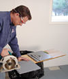 installing a waterproof vapor barrier on a basement floor to prepare for basement carpeting in a Saint Marys home